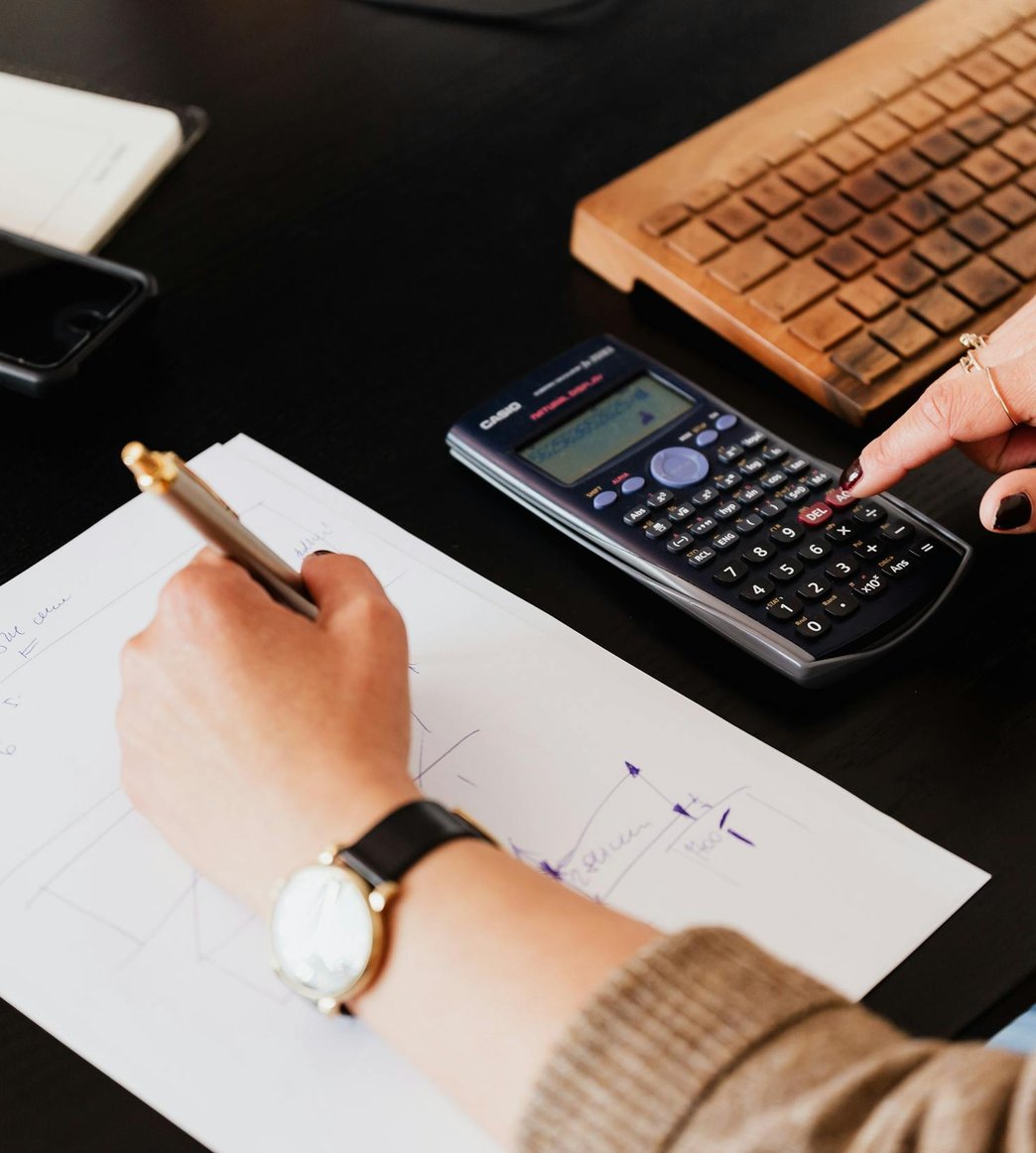 Bookkeeper writing notes on a financial worksheet beside a calculator